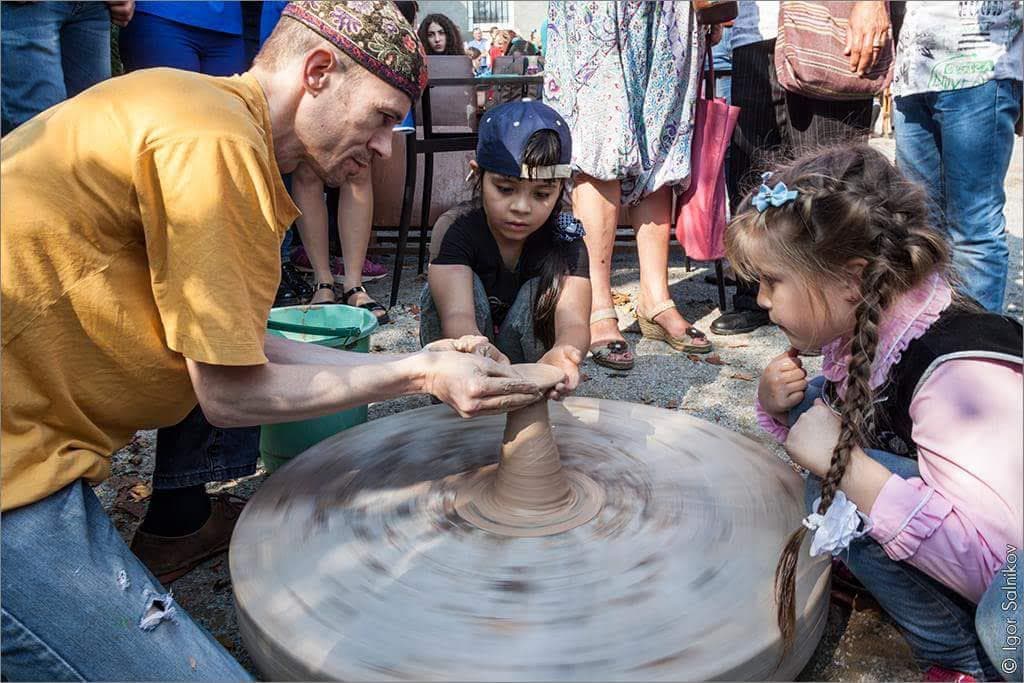 Children watching a pottery demonstration during a community workshop.